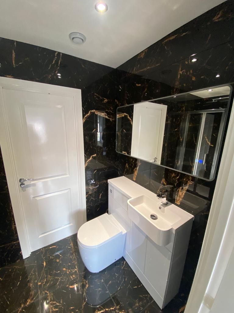 Cloakroom in black marble-effect tiles with a white vanity