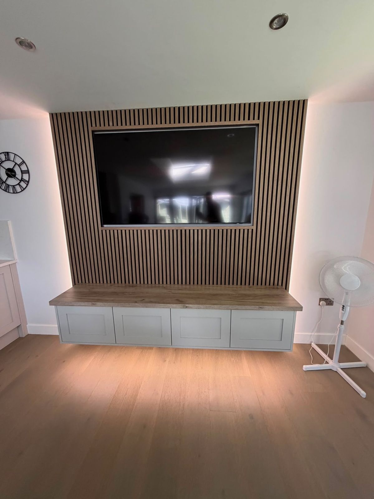 Media wall with oak slat panelling and built-in cabinetry