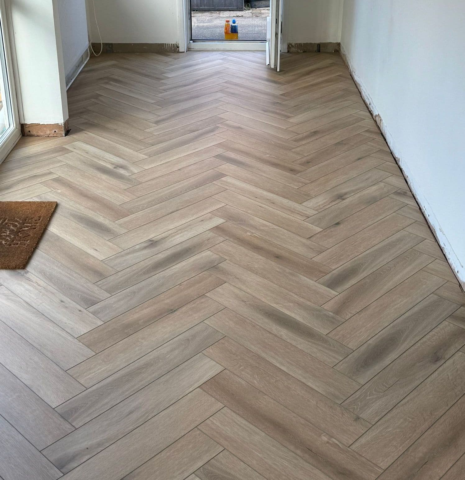 Light oak herringbone flooring laid through an open doorway, fitted by Coyne Flooring