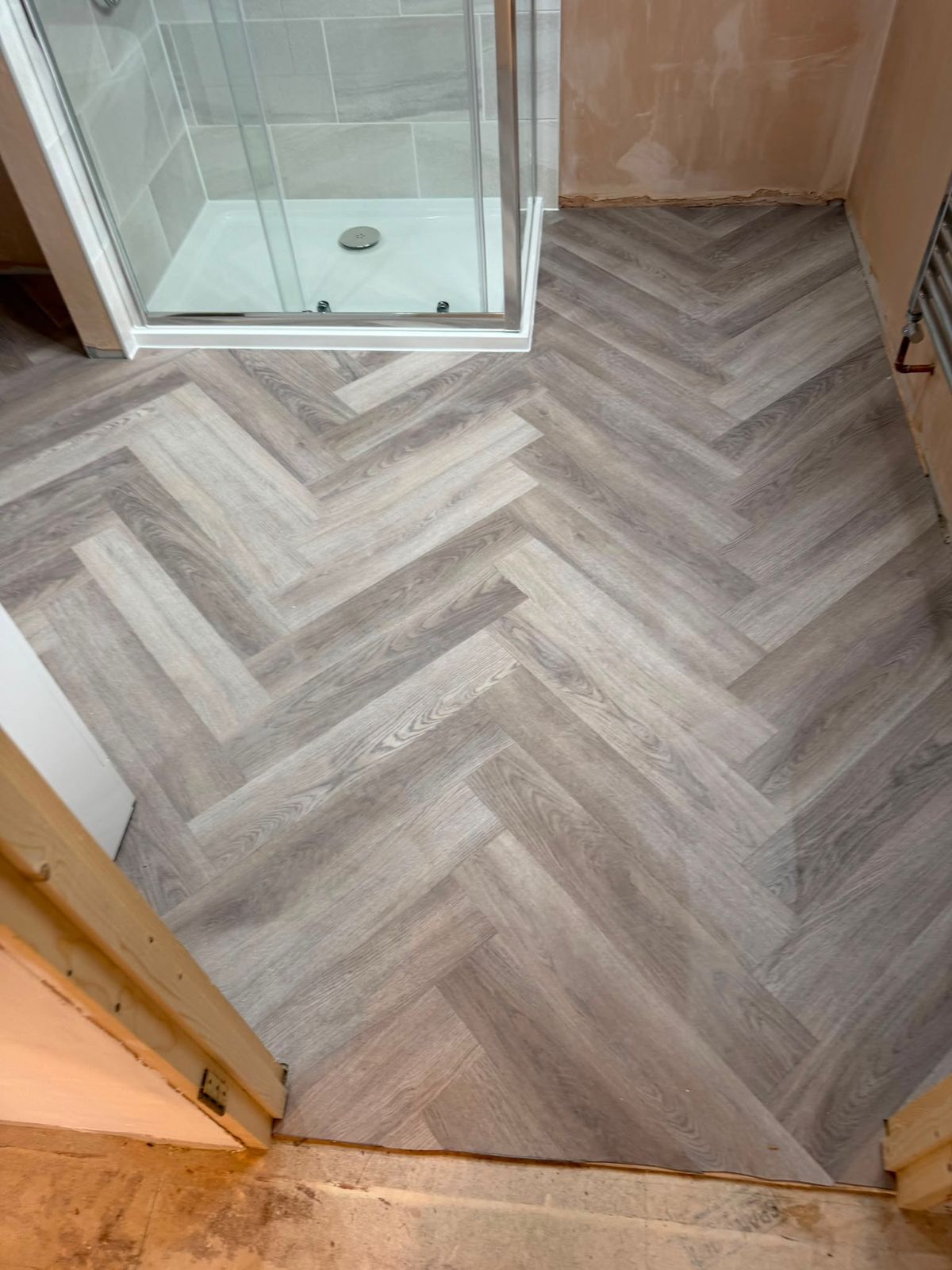Grey herringbone luxury vinyl laid through a bathroom refit