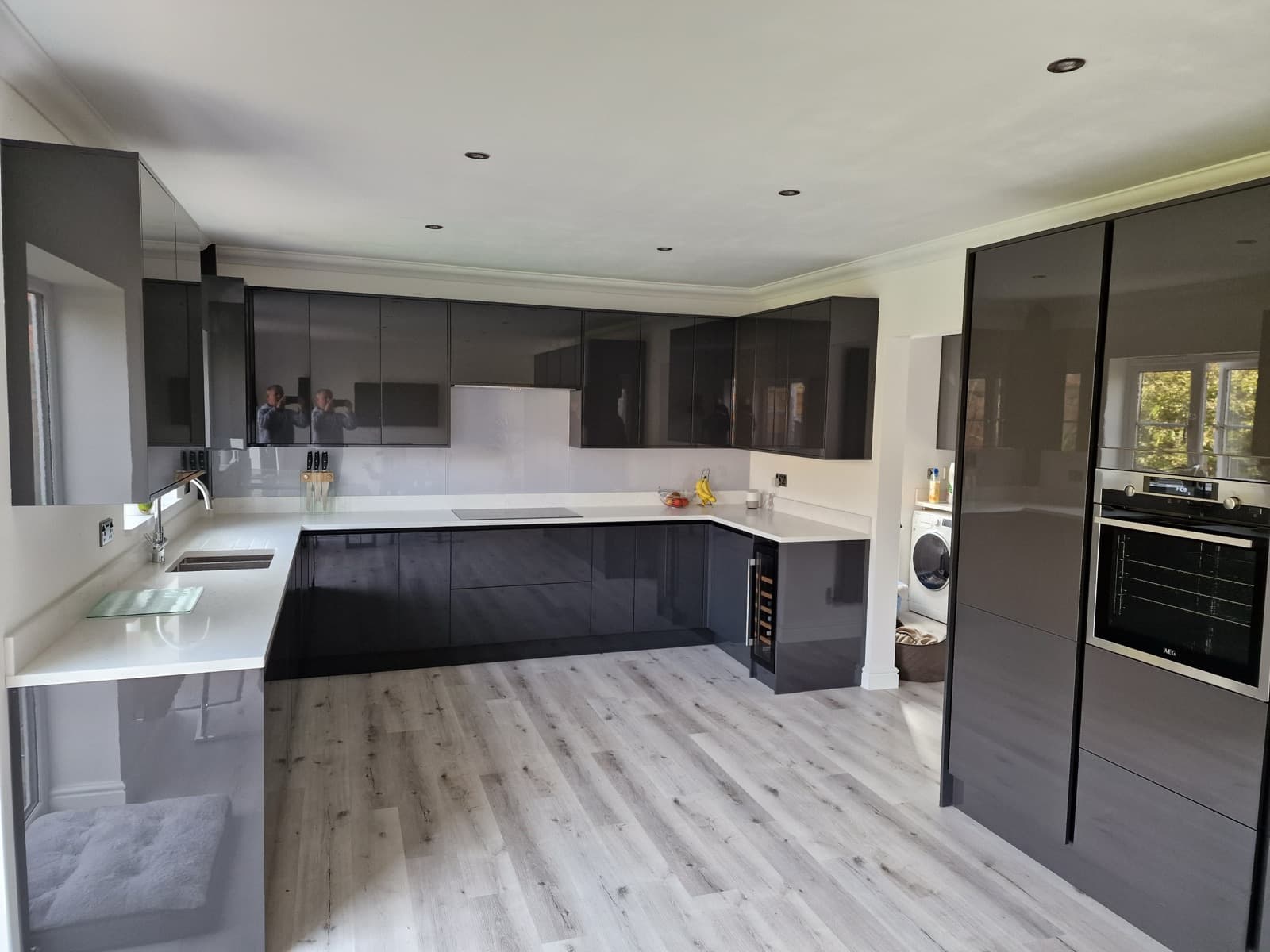 Coyne-fitted grey gloss handleless kitchen with white quartz worktops and oak-effect flooring