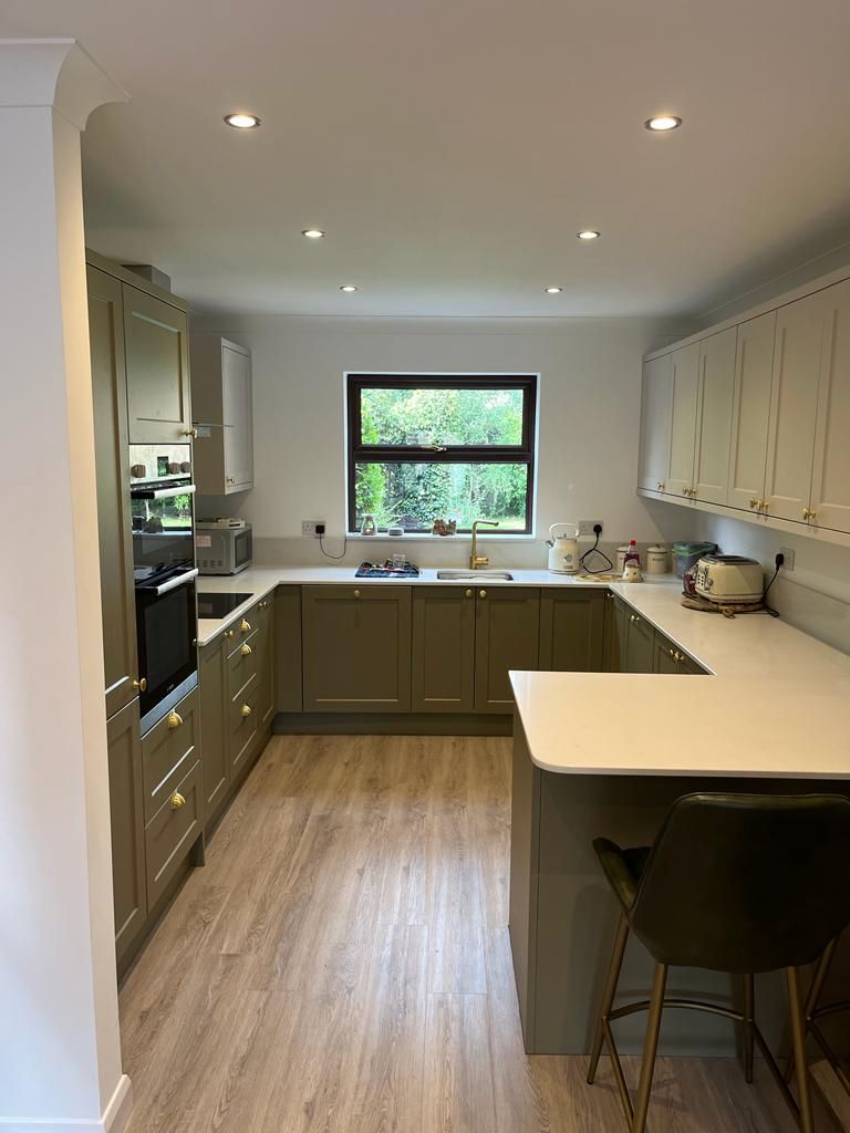 Sage green shaker kitchen with white worktops and a breakfast peninsula