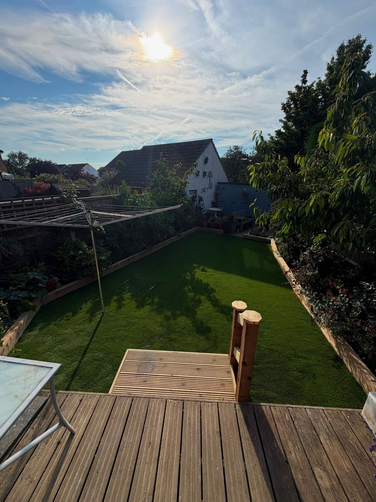 Low-maintenance artificial lawn with sleeper edging and decking